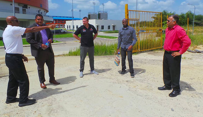 Anthony Creed points to a location on site behind the National Cycling Velodrome as Minister Smith, second from left, Erin Hartwell, centre, Trevlon Hall, second from right, and Jason Williams look on.