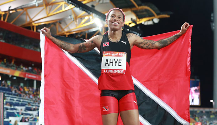 Michelle-Lee Ahye displays the national flag after winning the 100m gold at the Commonwealth Games at Carrara Stadium, Gold Coast, Australia, recently.