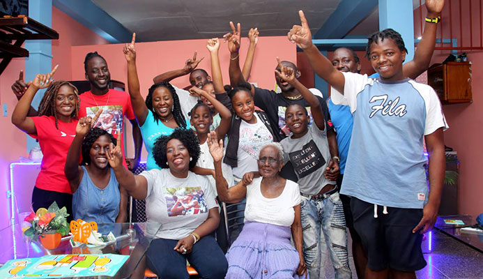 Relatives and friends of Jereem Richards, including his mother Yvette Wilson (seated center) and grandmother Deaprice Wilson (seated right) celebrate his victory at the family’s home in Point Fortin yesterday.