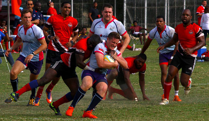 Bermuda’s Conor McGowen, centre, is tackled by TT’s Jason Quashie in their RAN 15s Tournament clash recently at St Anthony’s Ground, Westmoorings.