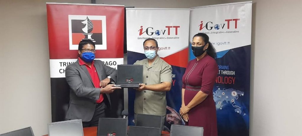 iGovTT acting deputy CEO Sherwin Ragoonanan, left, presents acting Supt. of Prisons Allan Nanan with ten laptops for prisoners' use at the Inter-Continental Chess Championships next week. At right is local chess association president Sonja Johnson. - TTCA